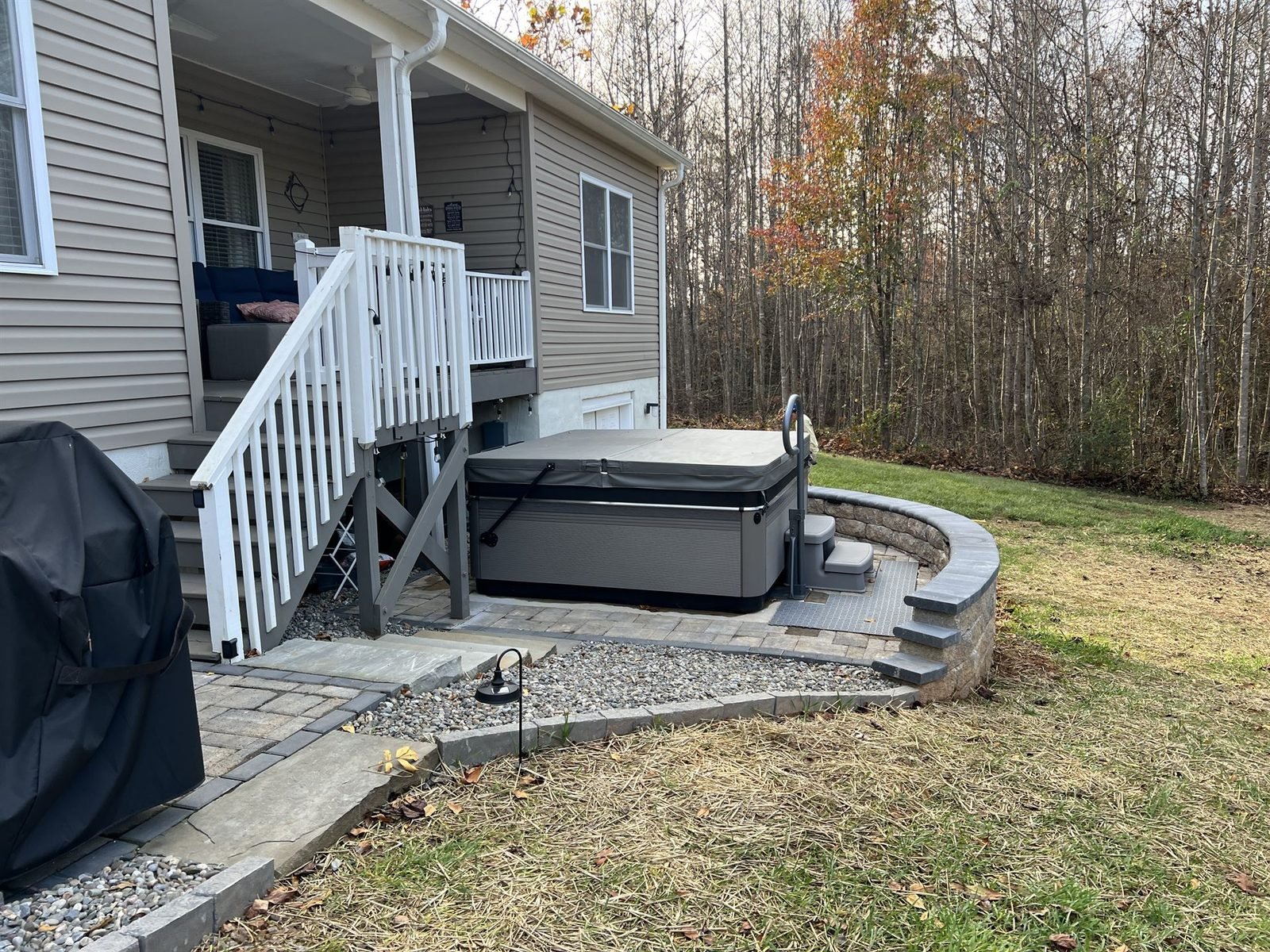 Completed paver patio with curved retaining wall and hot tub installation in Western NC by Black Oak Hardscapes