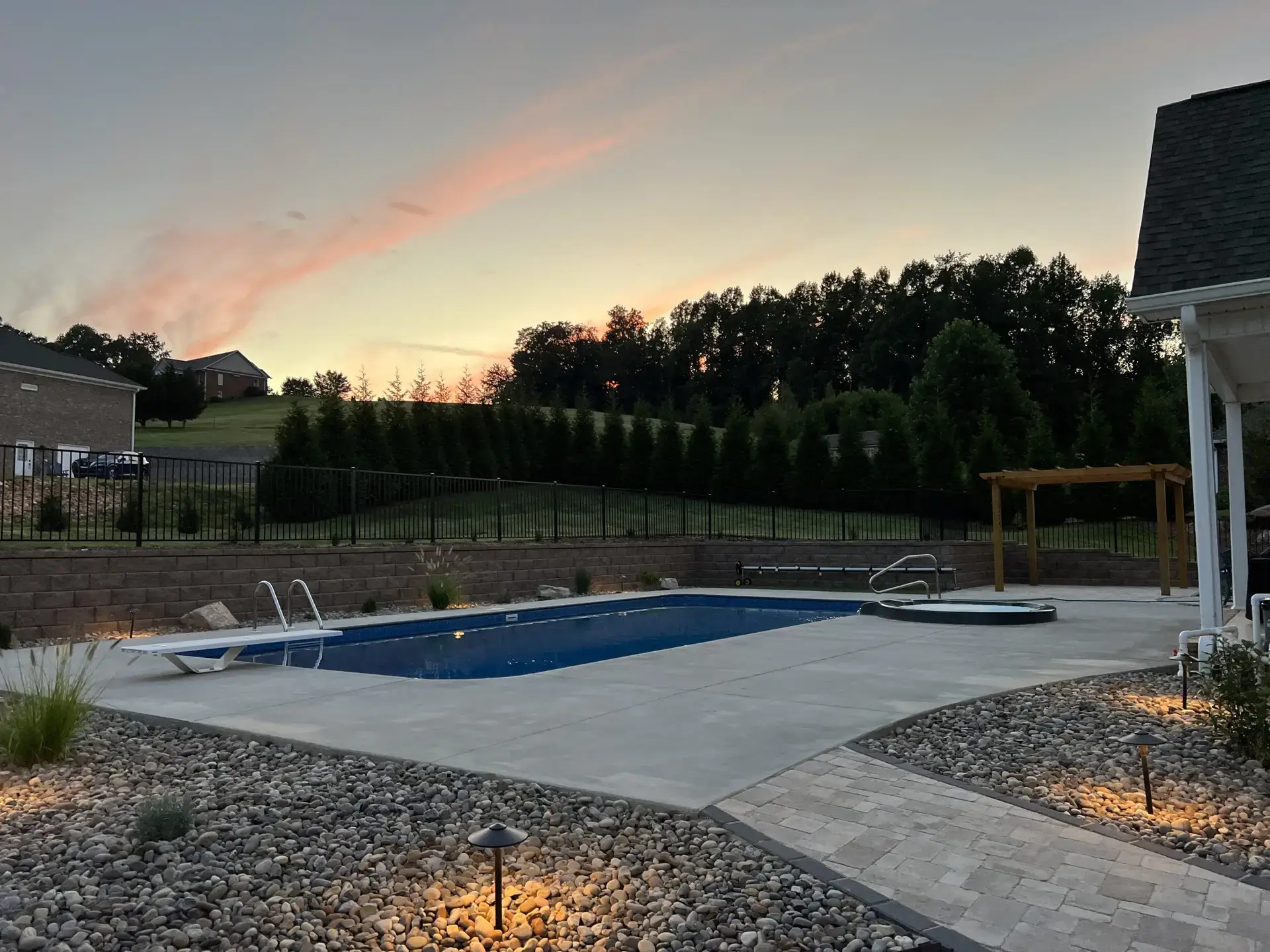 Poolside hardscape with paver patio, retaining wall, and pergola